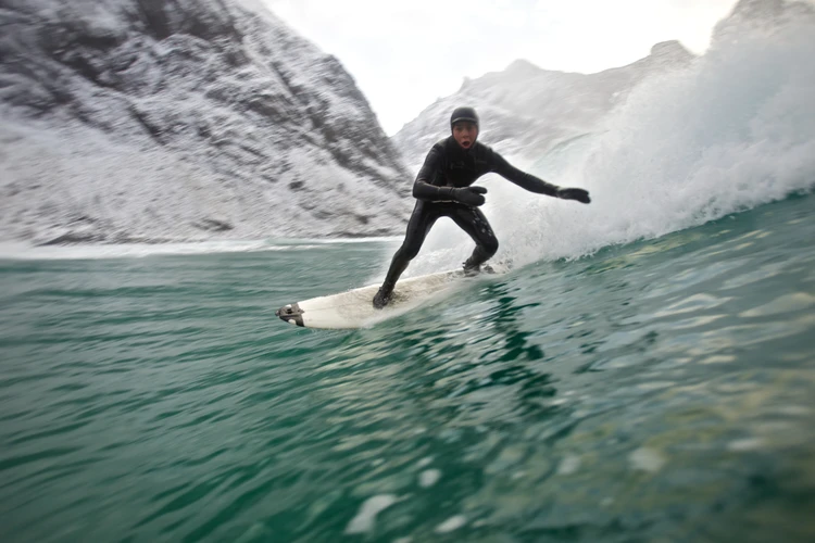 Ein Surfer reitet eine Welle mim Polarmeer.